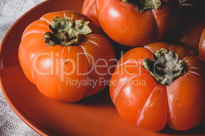 Fresh persimmons on orange plate