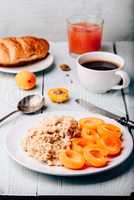 Porridge with apricot, coffee, glass of juice and croissant