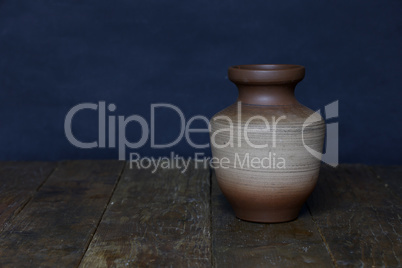 Beautiful clay vase stands on the wooden floor