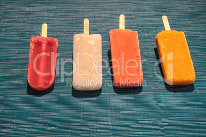 Fruit popsicles on an aqua blue background in summer