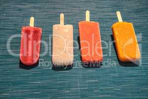 Fruit popsicles on an aqua blue background in summer