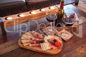 Red wine with Charcuterie board on rustic wood with candles behi