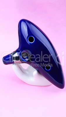 Blue Ceramic Ocarina with stand on pink background