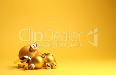 Three golden vintage Christmas baubles on a yellow background