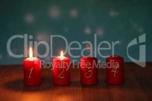 Red Advent candles stand on a wooden floor