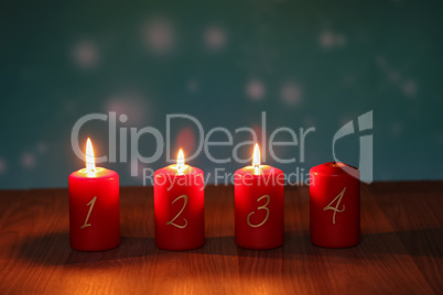 Red Advent candles stand on a wooden floor