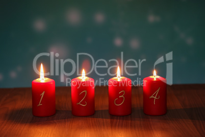 Red Advent candles stand on a wooden floor