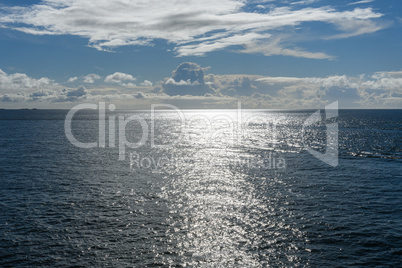 Cloudy blue sky leaving for horizon above a blue surface of the