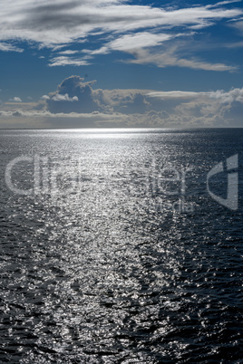 Cloudy blue sky leaving for horizon above a blue surface of the