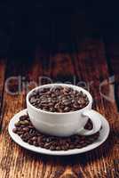 White cup full of roasted coffee beans