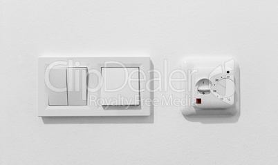 Pair of simple light switches with dimmer. Inexpensive plastic mechanical double switch with thermostat against white wall. Old air conditioner control panel. Smart Home Climate Control Appliances