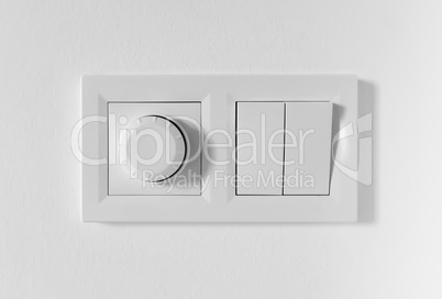 Pair of simple light switches with dimmer. Inexpensive plastic mechanical double switch with thermostat against white wall. Old air conditioner control panel. Smart Home Climate Control Appliances