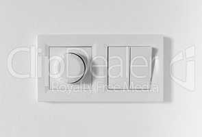 Pair of simple light switches with dimmer. Inexpensive plastic mechanical double switch with thermostat against white wall. Old air conditioner control panel. Smart Home Climate Control Appliances