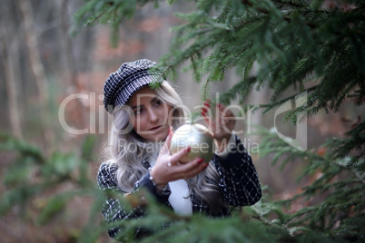 Girl hangs a beautiful Christmas ball on a fir tree