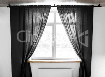 Two separate linen curtain panels with tieback in classic and contemporary bedroom. Panel pair cotton curtains tied back at the modern window. Semi-sheer black floor length curtains on the metal rod.