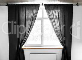 Two separate linen curtain panels with tieback in classic and contemporary bedroom. Panel pair cotton curtains tied back at the modern window. Semi-sheer black floor length curtains on the metal rod.