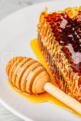 Honeycomb on plate with honey dipper