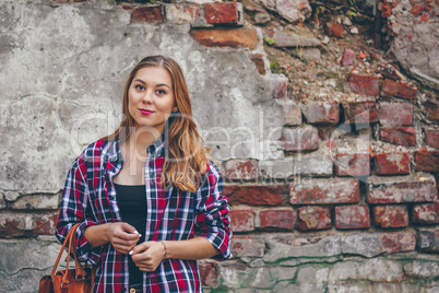 Beautiful girl is standing against brick wall