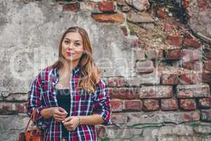 Beautiful girl is standing against brick wall