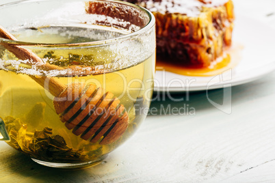 Honey dipper in cup of green tea