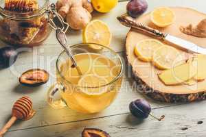 Cup of tea with lemon, honey and ginger over wooden surface