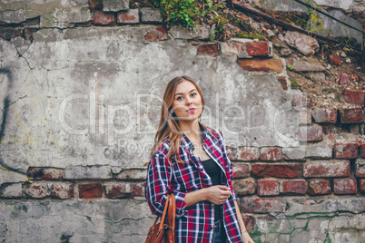 Beautiful girl is standing against brick wall