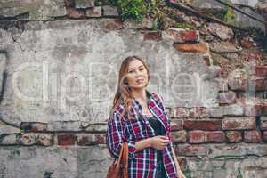 Beautiful girl is standing against brick wall