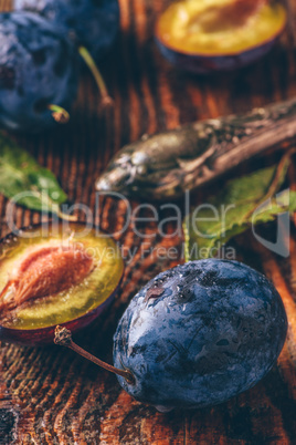 Ripe plums with leaves, water drops and knife