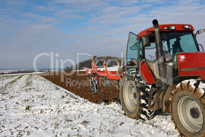 Tractor at work plowing a field in winter