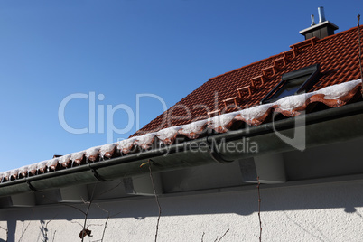 The snow on the roof melts and forms ice icicles