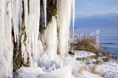 Huge icicles hanging from the rocks, frozen waterfall with views of the sea