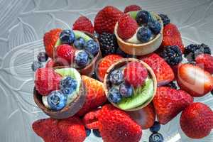 Fruit tarts on top of mixed berry background that includes red s