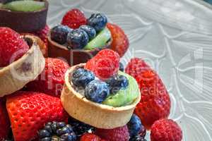 Fruit tarts on top of mixed berry background that includes red s