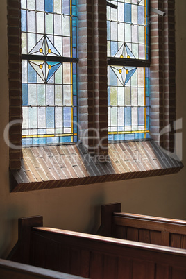 Wooden pews in an old Dutch church with a colorful stained glass