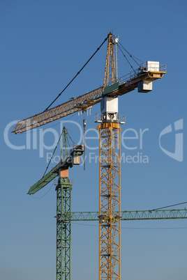 Three cranes in the evening light on a large construction site i