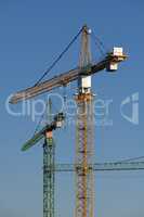 Three cranes in the evening light on a large construction site i