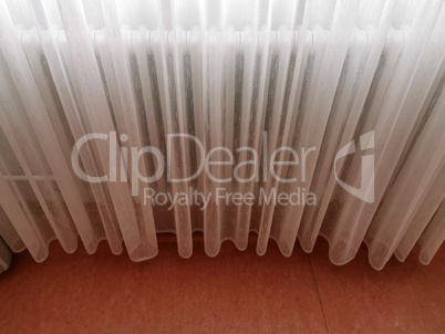 A transparent white curtain covers the radiator