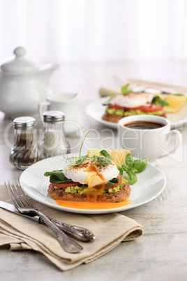 Eggs Benedict with guacamole on cereal bread