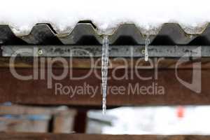 The snow on the roof melts and forms ice icicles