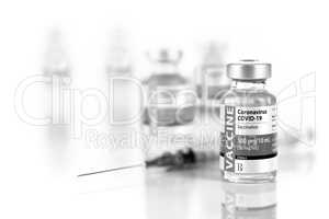 Coronavirus COVID-19 Vaccine Vials and Syringe On Reflective Sur
