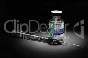 Syringe Needle and Coronavirus COVID-19 Vaccine Vial Spot Lit on