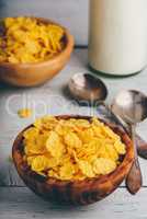 Bowl of corn flakes with spoons and bottle of milk