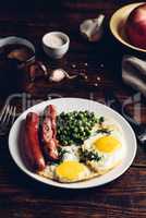 Breakfast with fried eggs, sausages and green peas