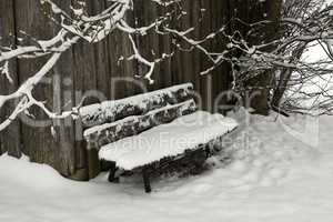 Old wooden bench in winter covered with snow