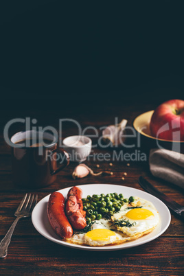 Breakfast with fried eggs, sausages and green peas