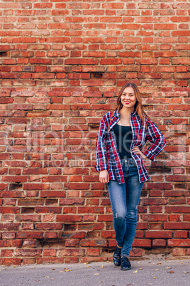 Portrait of young woman standing against brick wall