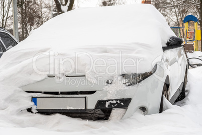 City street after blizzard. Stuck cars under the snow and ice. Buried vehicle in snowdrift on the road. Parking lots in winter after heavy snowfall. Uncleaned roads. Record-breaking amounts of snow.