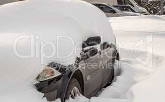 City street after blizzard. Stuck cars under the snow and ice. Buried vehicle in snowdrift on the road. Parking lots in winter after heavy snowfall. Uncleaned roads. Record-breaking amounts of snow.