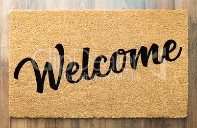 Tan Welcome Mat On Wood Floor Background.