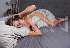 Schöne Frau umklammert die Zudecke im Bett Mit den Beinen